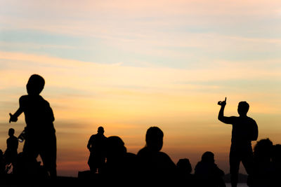 Silhouette people standing against sky during sunset