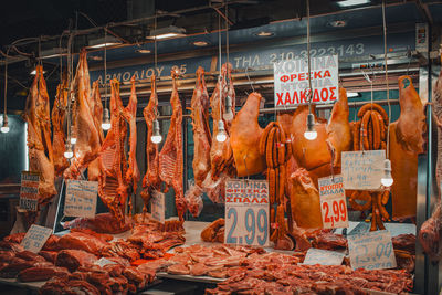 Local vendor stand w/ multiple sorts of meet in central municipal athens market with price tags.