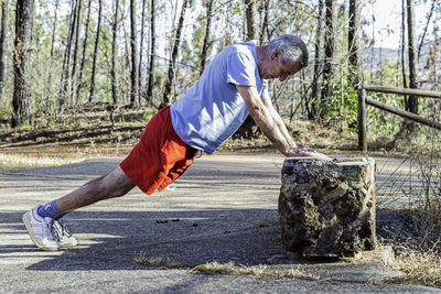 Side view of man exercising on footpath