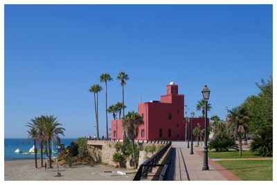 Palm trees on beach against clear blue sky. red castle. 