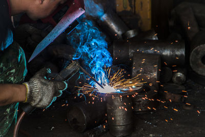 Side view of welder welding metal in workshop