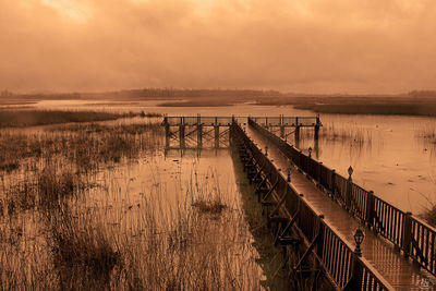 Pier over lake against sky during sunset