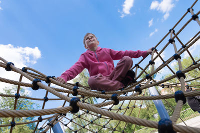 Low angle view of child on slide in playground against sky