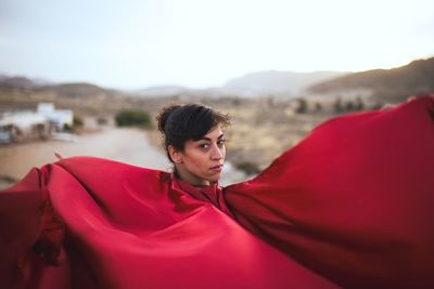 Portrait of woman in red dress against sky