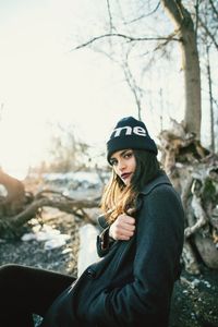 Portrait of young woman wearing hat against trees