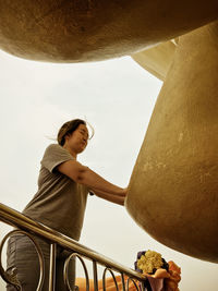 Low angle view of woman touching statue while praying