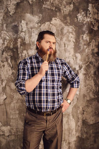 Thoughtful mature man standing against wall