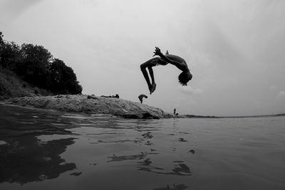 Man jumping in sea against sky