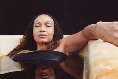 Portrait of beautiful young woman with eyes closed against black background