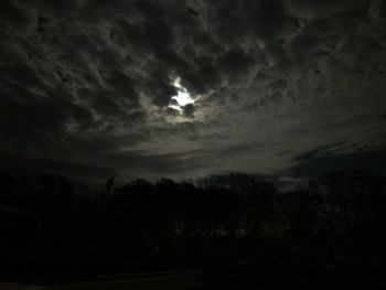 Silhouette of trees against cloudy sky