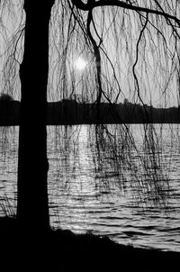 Silhouette bare tree by lake against sky