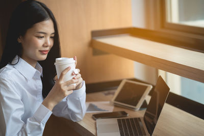 Young woman drinking coffee cup on table