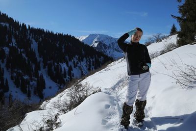 Portrait of woman saluting while standing on snowcapped mountain