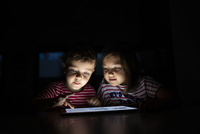 Brother using digital tablet by sister at home