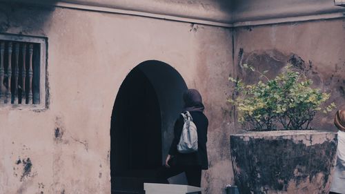 Man standing by window on wall of building