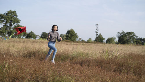 Full length of happy young woman standing on field