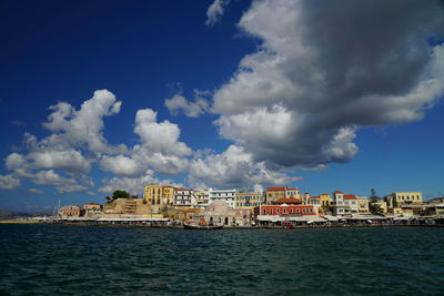 View of cityscape by sea against sky