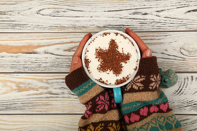 Cropped hands of woman holding coffee cup on table