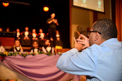 Man gesturing to people sitting on stage