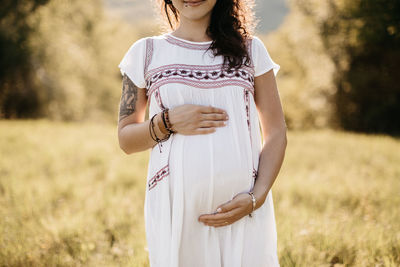 Midsection of pregnant woman standing on grassy field