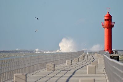 Lighthouse by sea against sky