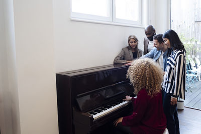 Businesswoman playing piano with singing colleagues