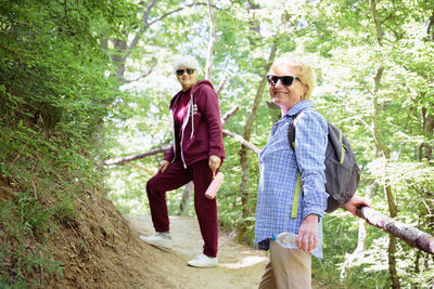Two mature woman spending vacations outdoors, walking in forest
