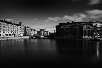 Parliament house by river against sky in city