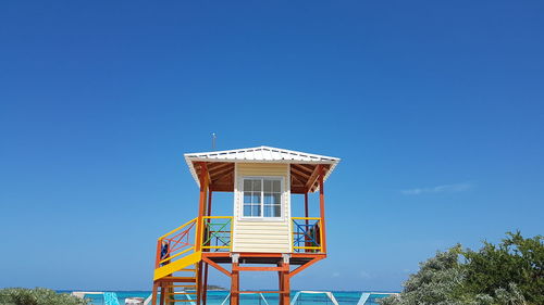 Low angle view of hut on beach against clear blue sky