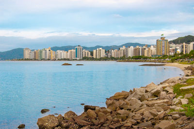 Buildings by sea against sky