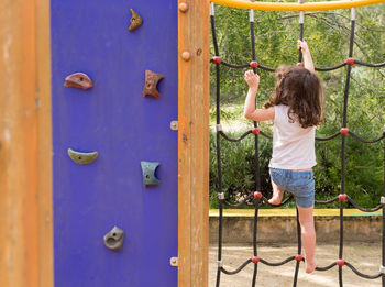 Rear view of girl climbing on jungle gym at playground