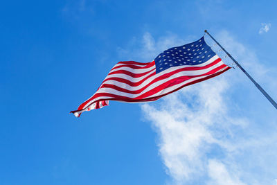 American flag blowing in the wind with a blue sky