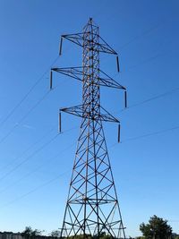 Low angle view of electricity pylon against blue sky