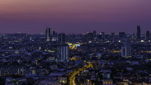 Illuminated cityscape against sky during sunset