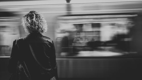 Rear view of woman standing on train at railroad station