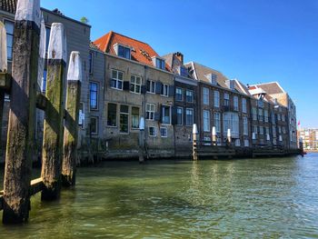 Canal by buildings against clear sky