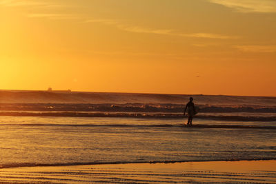 Silhouette surfer walking on the beach