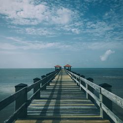 Pier on sea against cloudy sky