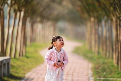 Cute girl standing amidst trees