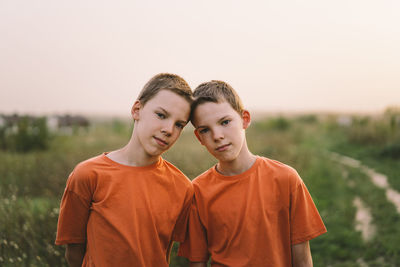 Funny twin brother boys playing outdoors on field at sunset.