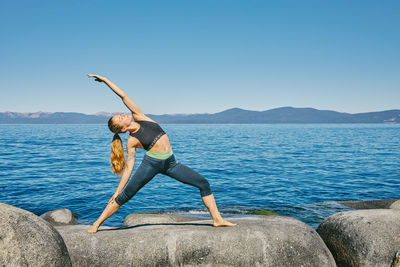 Young woman practicing yoga on lake tahoe in northern california.