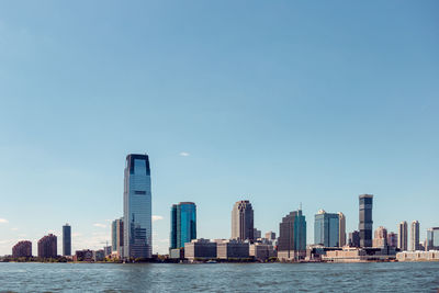 Sea by modern buildings against clear sky