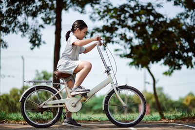 Full length of girl with bicycle against trees