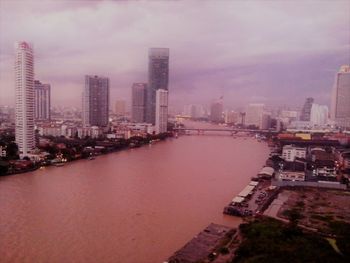 River amidst buildings in city against sky