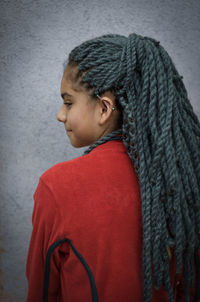 Rear view of woman with dreadlocks while standing against wall