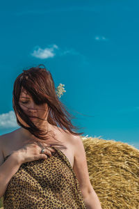 Portrait of woman standing against blue sky