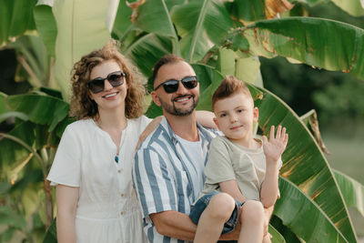 Portrait of woman wearing sunglasses while standing against plants