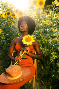 Woman sitting on yellow flower in field