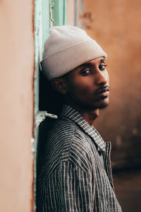 Side view of man leaning on wall