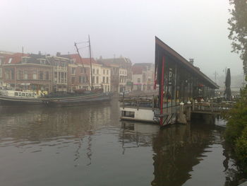 Boats in river in city against sky